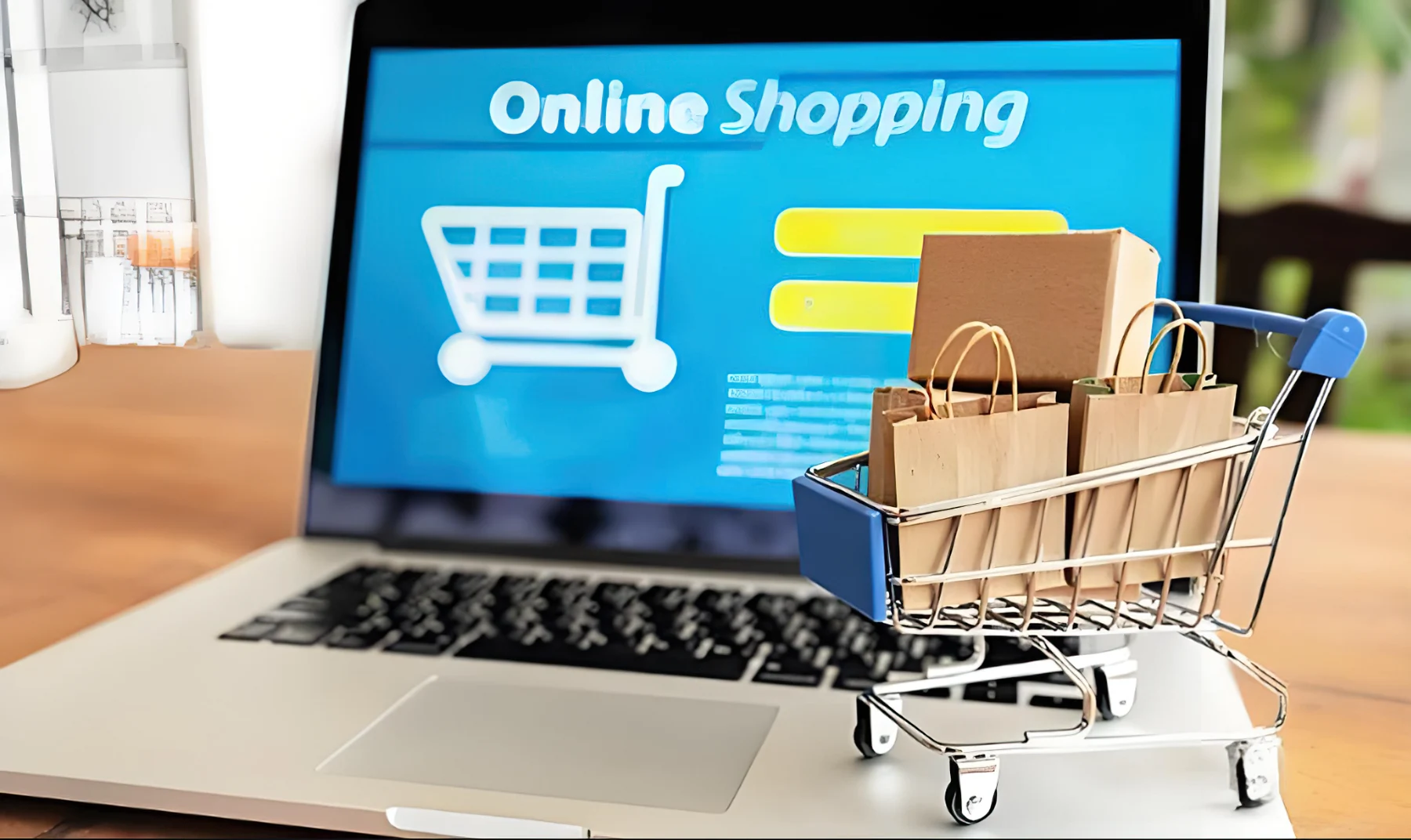 Shopping cart and bags beside an online storefront on a laptop